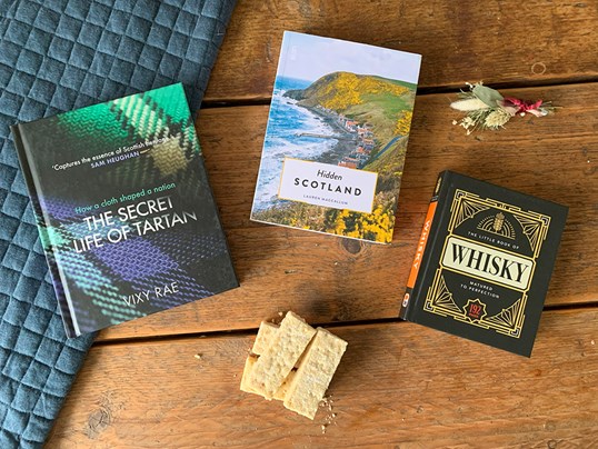 Scottish themed books scattered on a rustic table