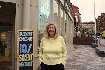 Woman in yellow jumper standing outside shop in Glasgow street