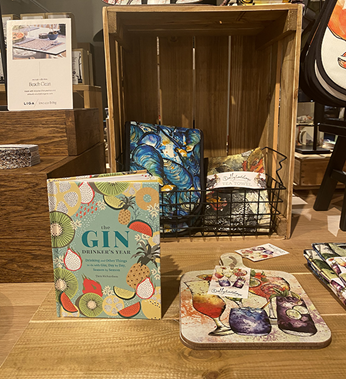 Gin book upright on a table surrounded by other products including colourful illustrated placemats.