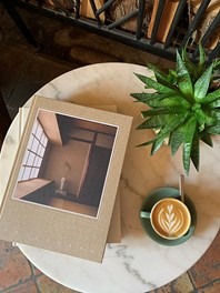 Books on a coffee table with a plant and a cup of coffee