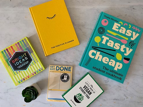 Books and school products spread out on a white marble effect background.