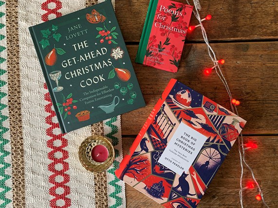 Christmas books spread out on a table surrounded by red fairy lights